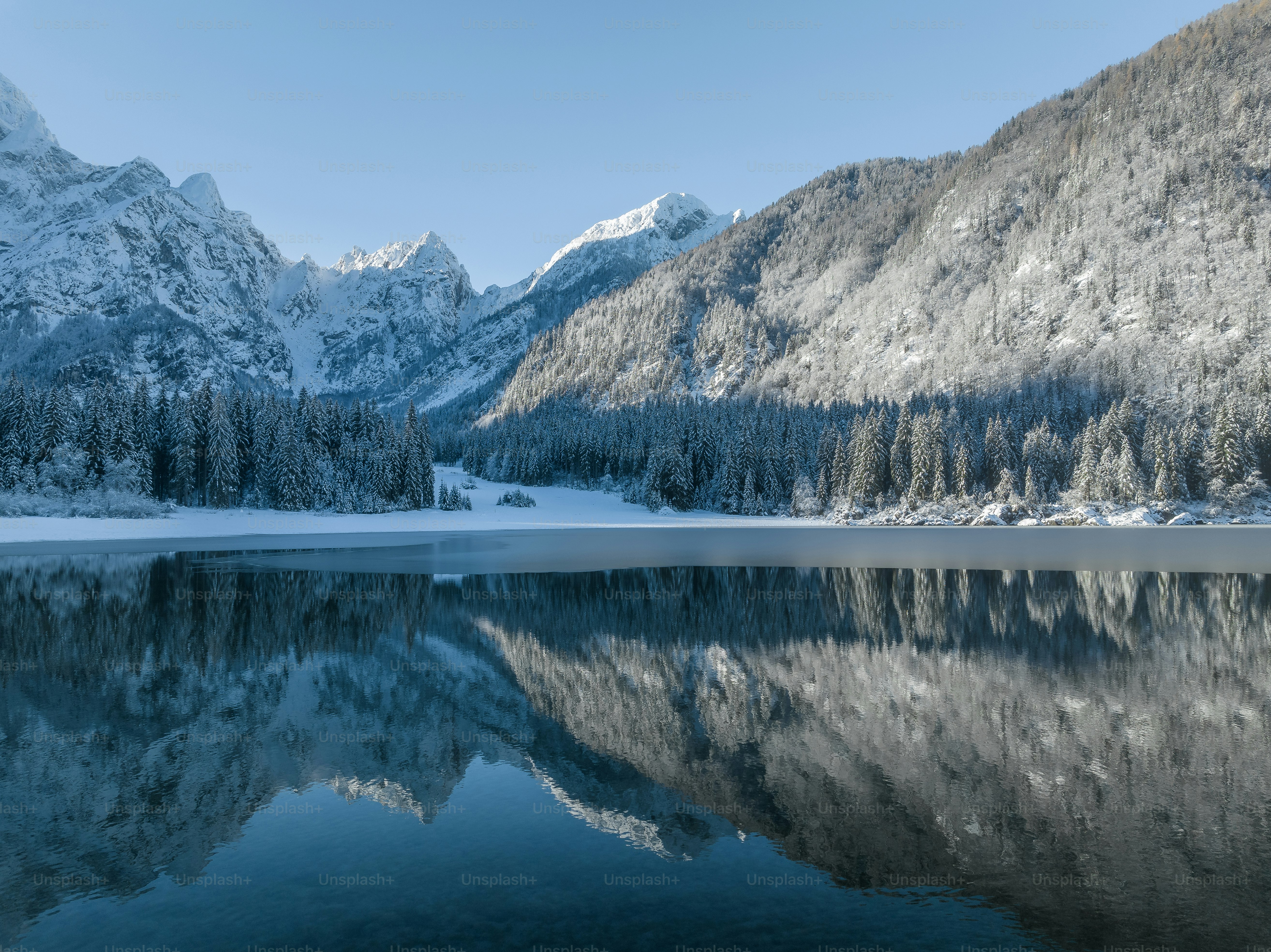 a lake surrounded by snow covered mountains and trees