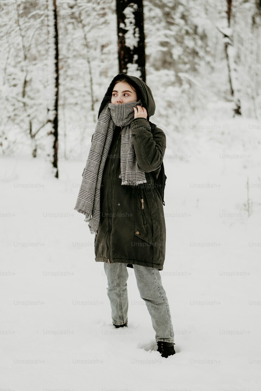 a woman standing in the snow with a scarf around her neck