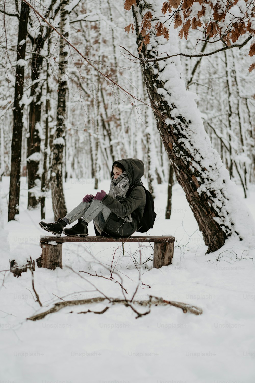 uma pessoa sentada em um banco na neve