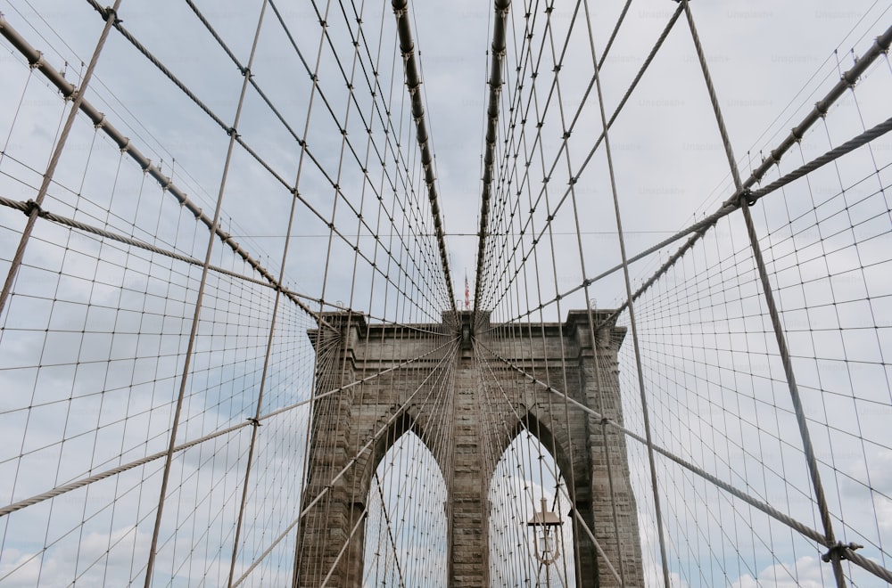 una torre alta con cables con el puente de Brooklyn al fondo