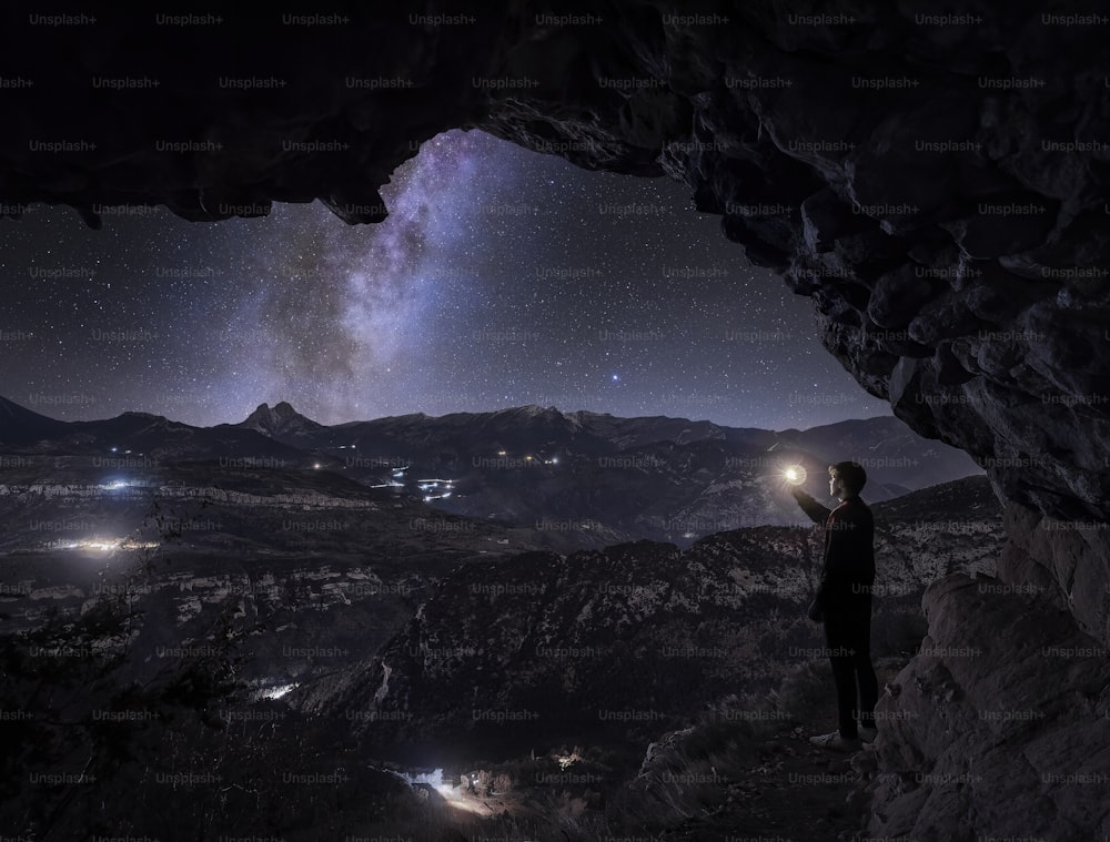 uma pessoa em pé em uma caverna olhando para as estrelas
