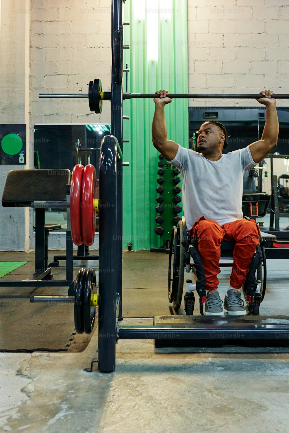 a man in a wheelchair lifts a bar in a gym