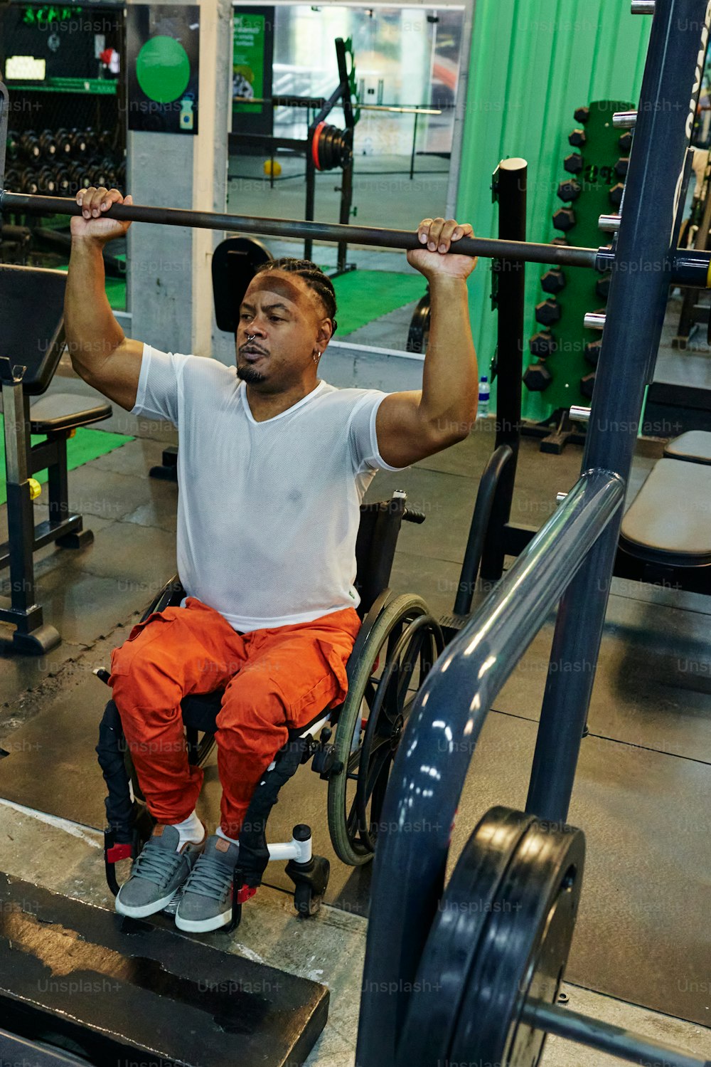 Ein Mann im Rollstuhl hebt eine Bar in einem Fitnessstudio