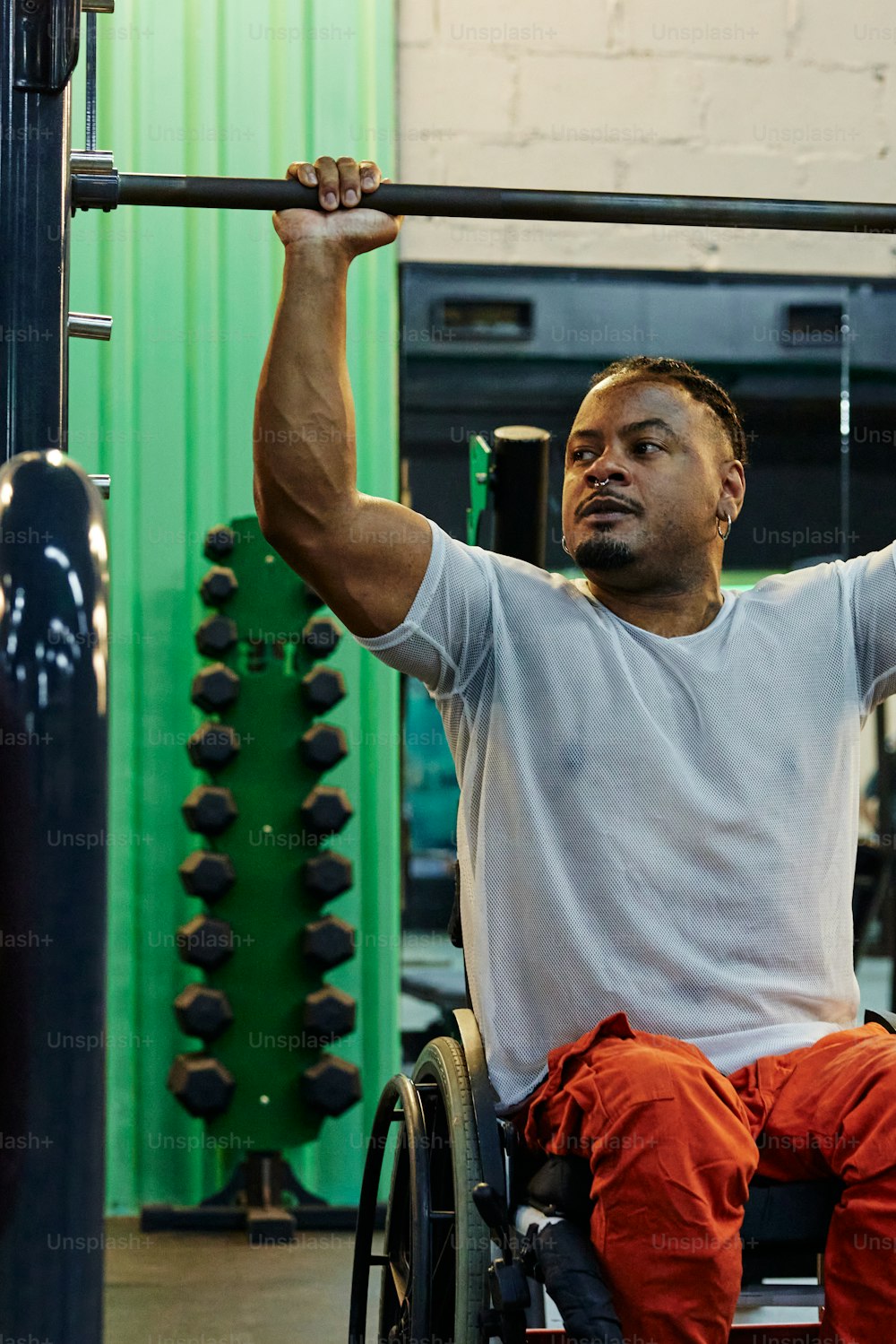 Un hombre en silla de ruedas levanta una barra en un gimnasio