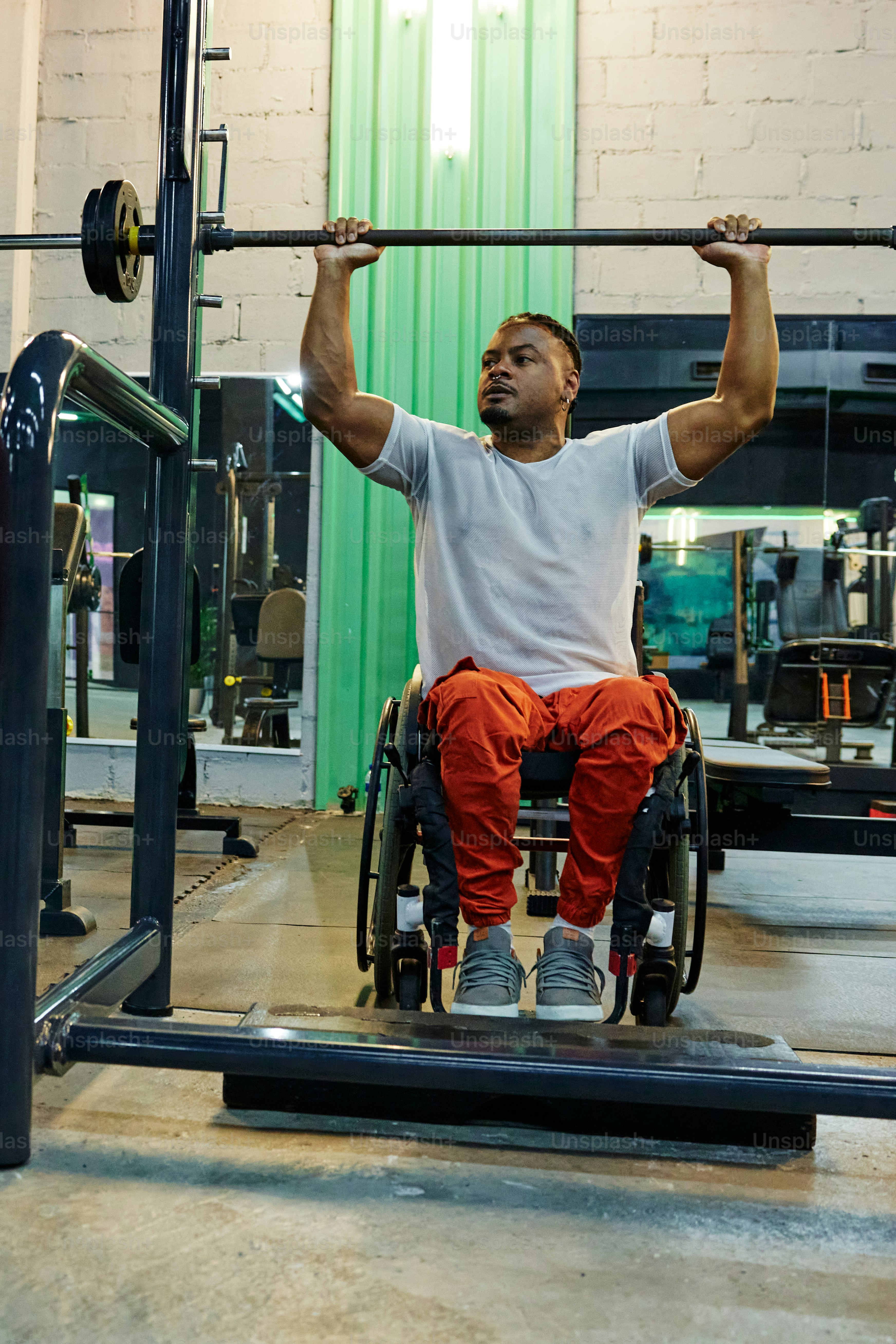 a man in a wheelchair lifts a bar in a gym