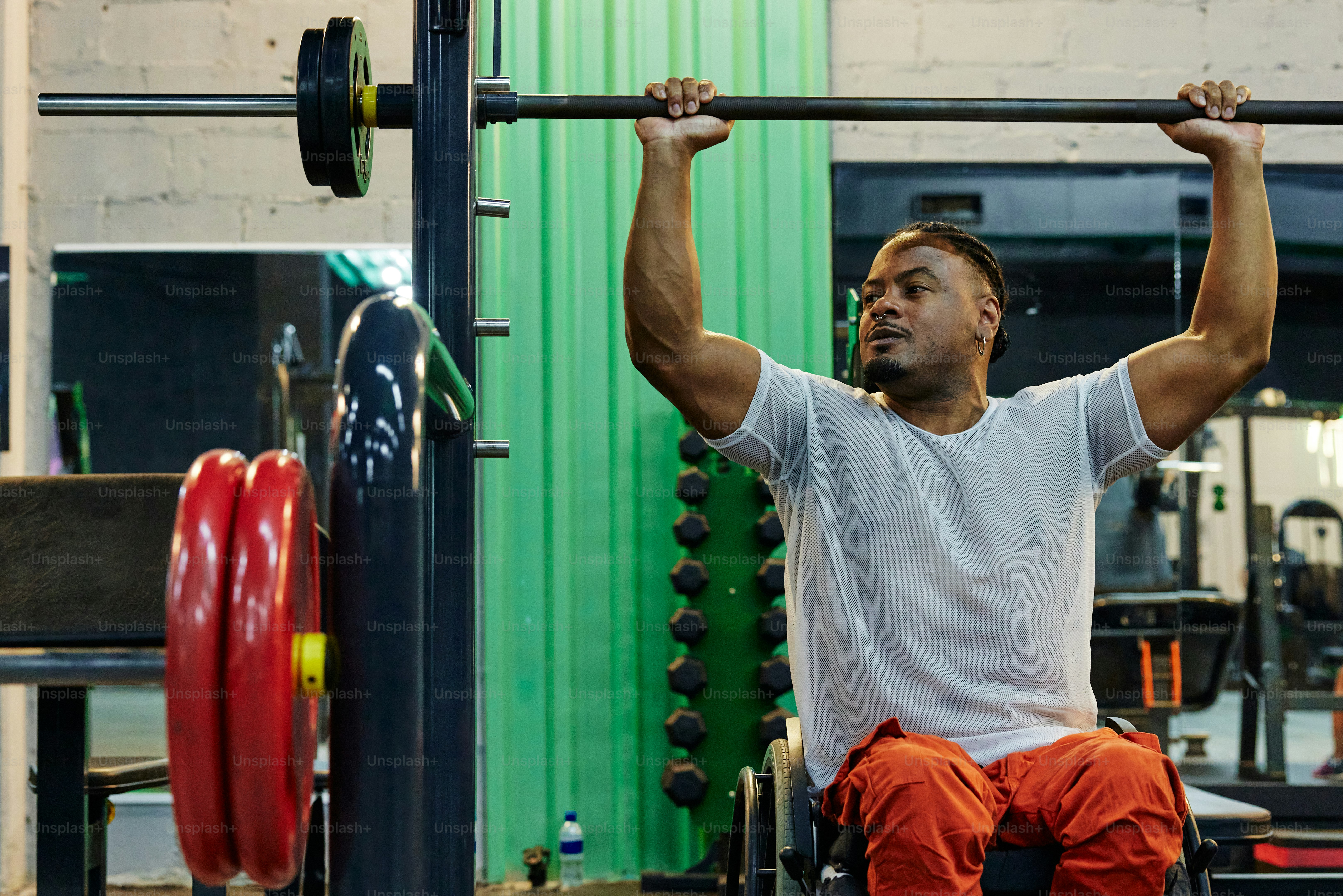 a man in a wheelchair lifts a bar in a gym