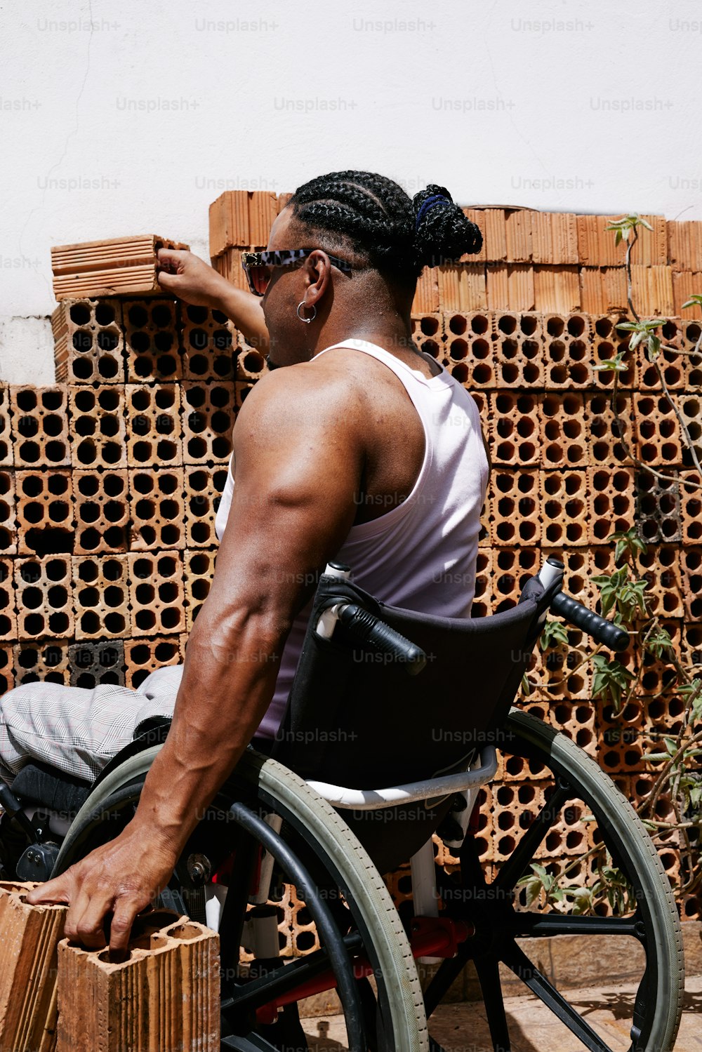 Un hombre en una silla de ruedas con un montón de ladrillos