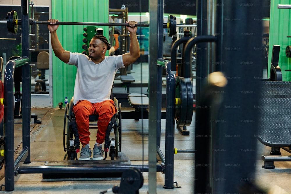 Un hombre en silla de ruedas levanta una barra en un gimnasio
