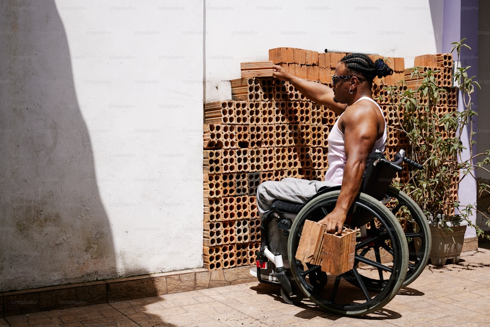 a man in a wheel chair pointing at a brick wall