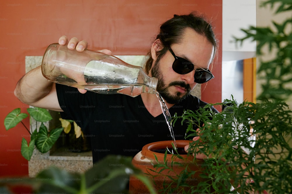 um homem está derramando água em um vaso de planta