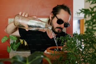 Un hombre está vertiendo agua en una planta en maceta