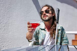Un hombre sentado en una mesa sosteniendo una copa de vino