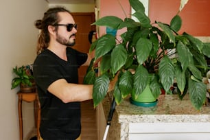 a man in a black shirt is holding a potted plant