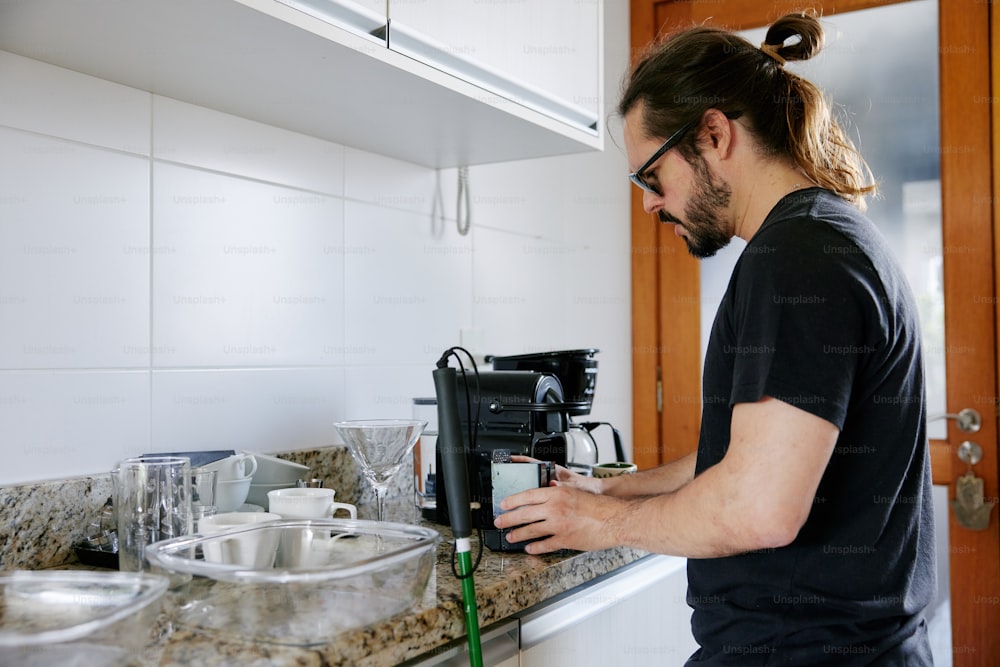 a man in a black shirt is using a coffee maker