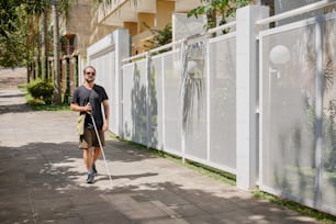 a man walking down a sidewalk with a cane