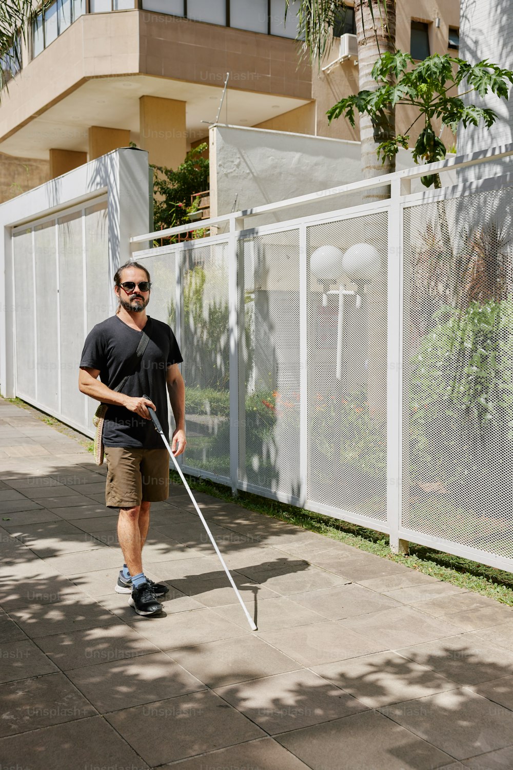 a man with a cane walking down a sidewalk