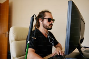 Un hombre sentado frente a una computadora con auriculares puestos