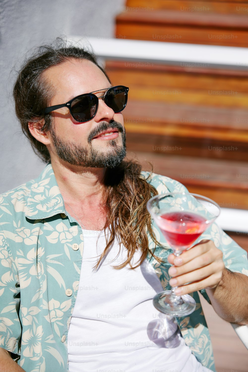 a man with long hair holding a wine glass