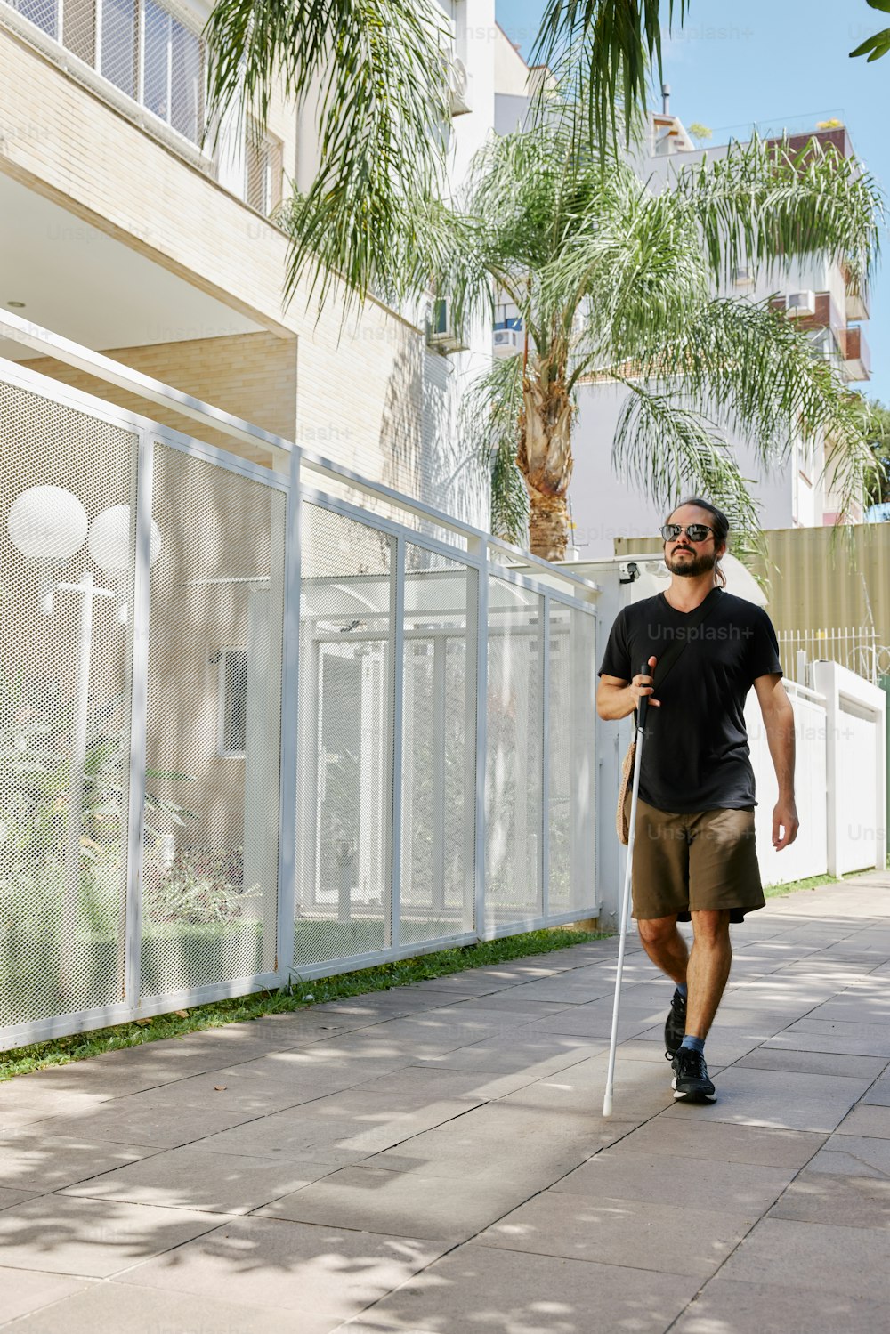 a man walking down a sidewalk with a cane