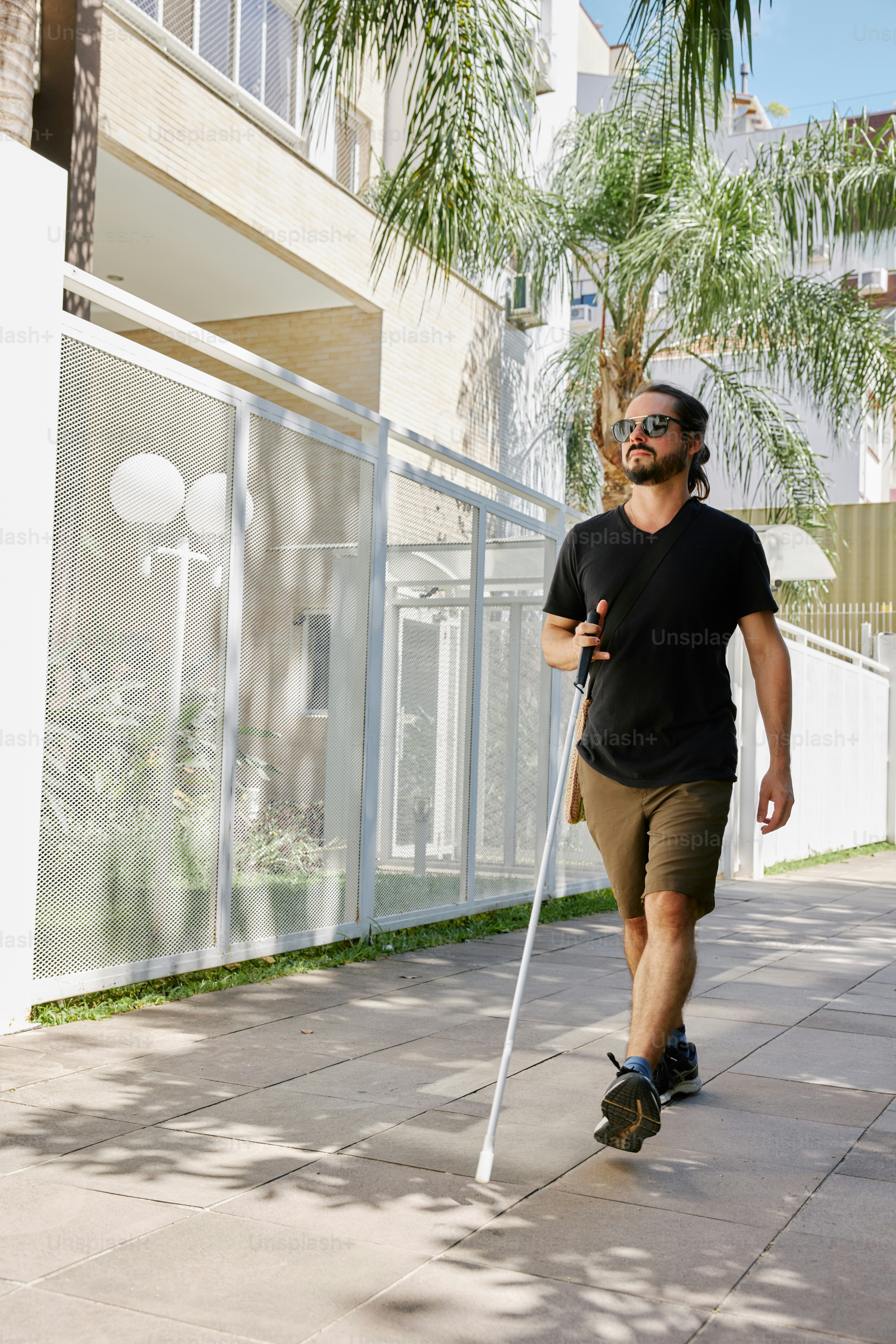 a man walking down a sidewalk with a cane