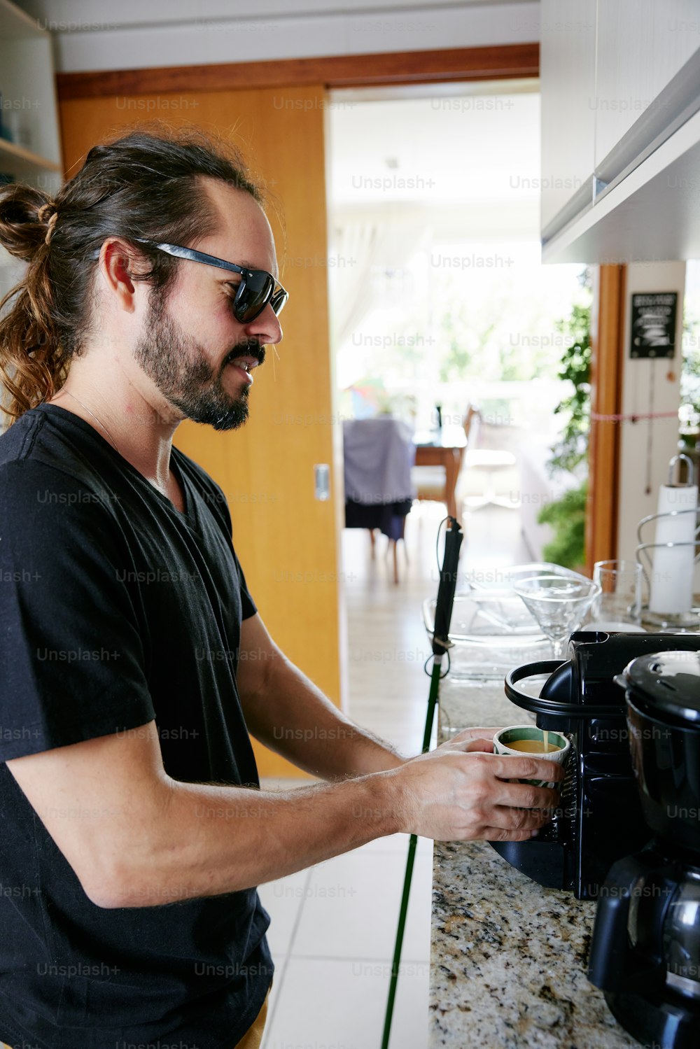 a man with a ponytail standing in a kitchen