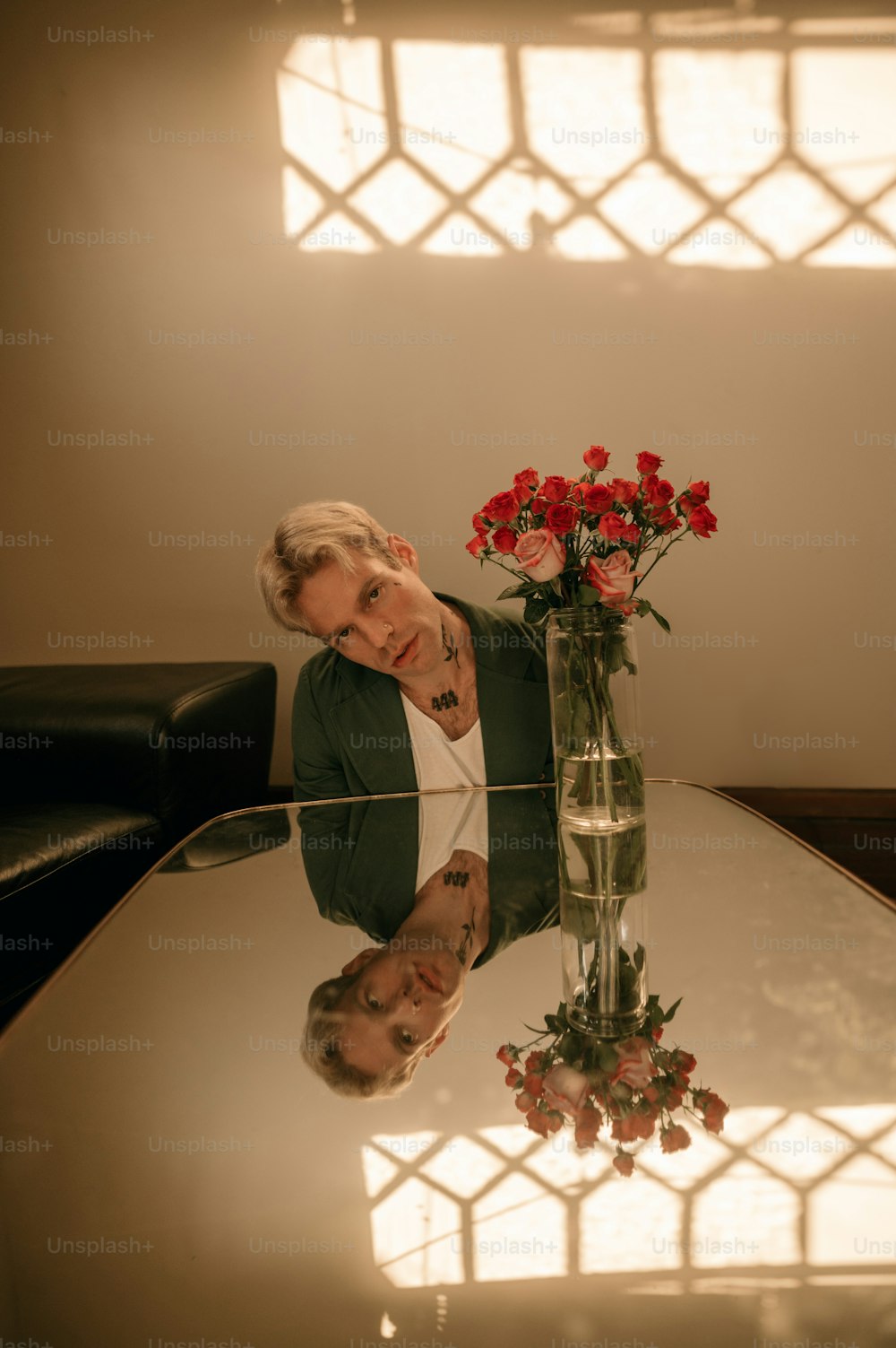 a person leaning on a table with a vase of flowers