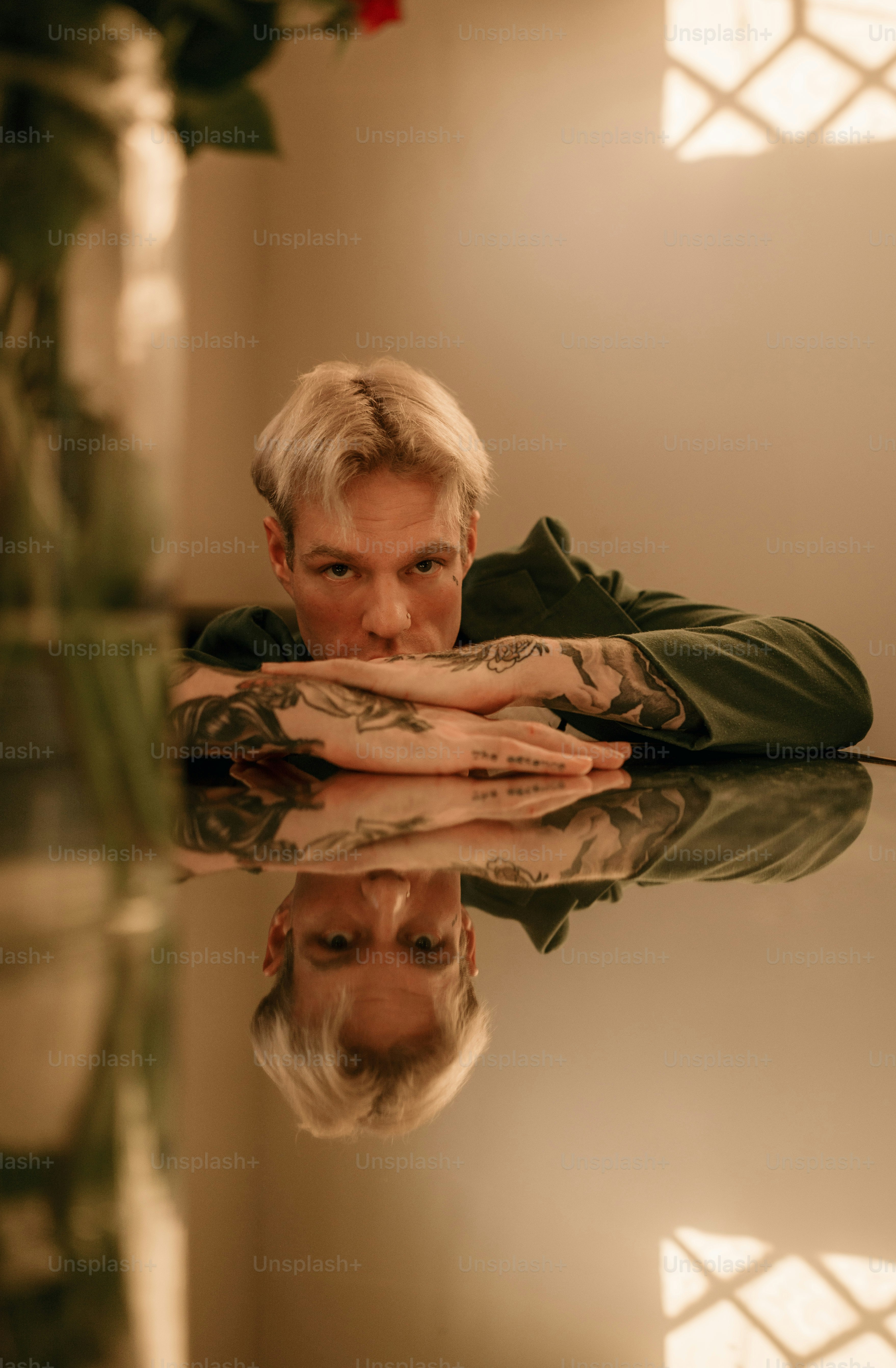 a man with white hair and tattoos leaning on a table