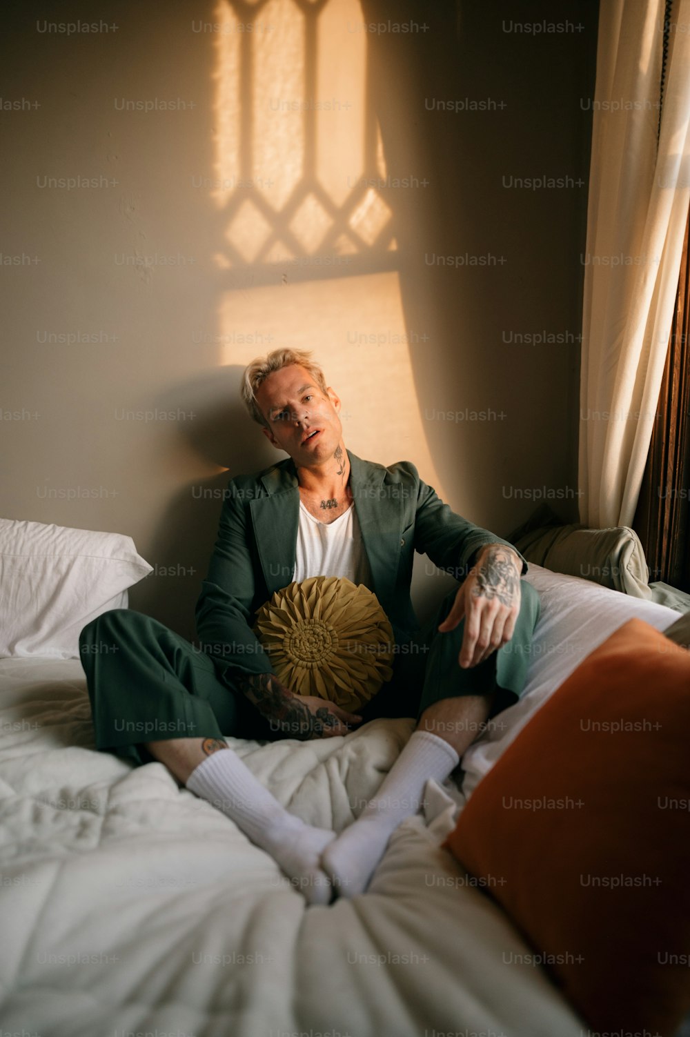 a person in a suit sitting on a bed with a pillow