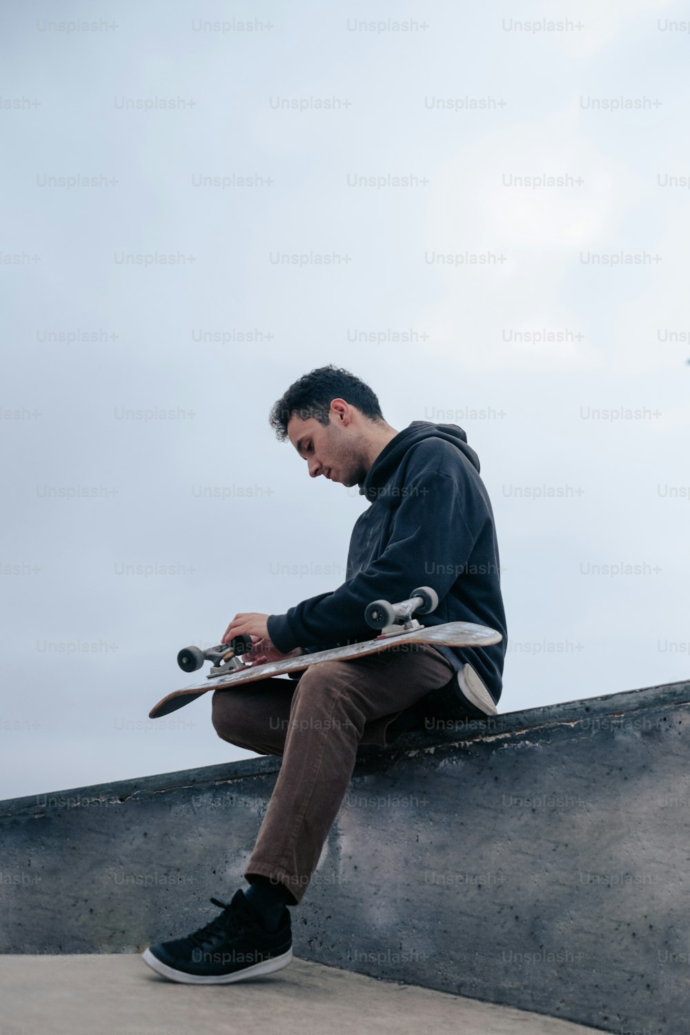 a man sitting on a ledge with a skateboard