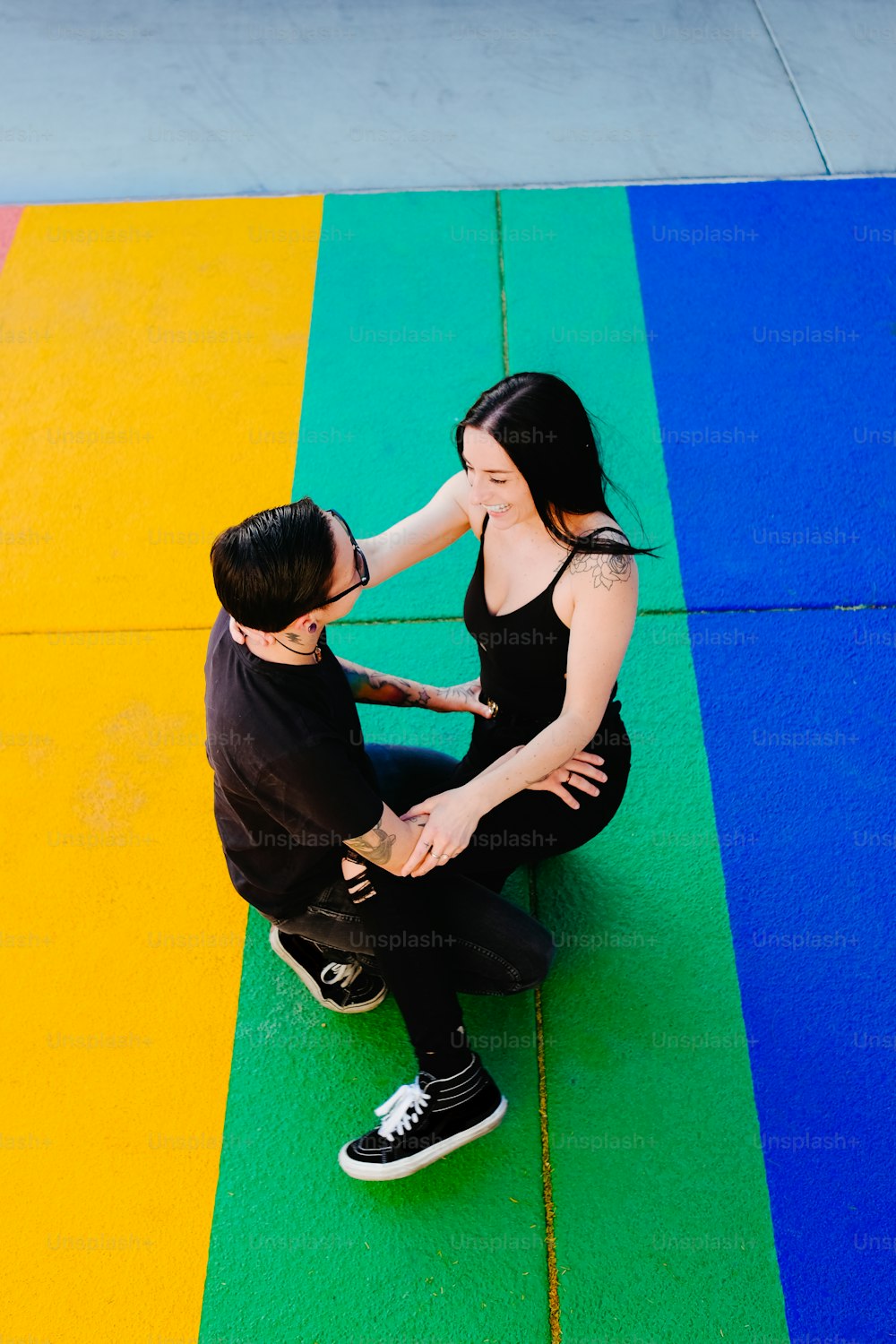 a man and woman sitting on a yellow and blue mat