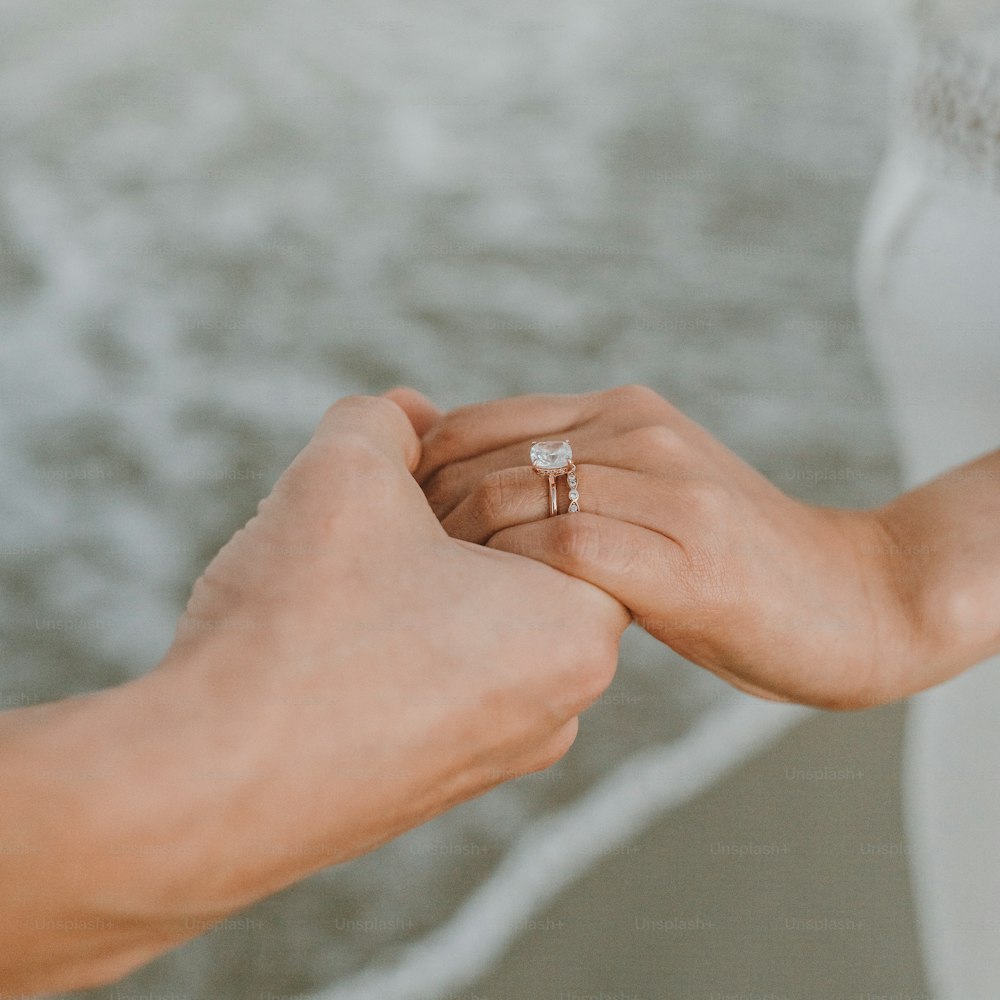 a pair of hands holding a wedding ring