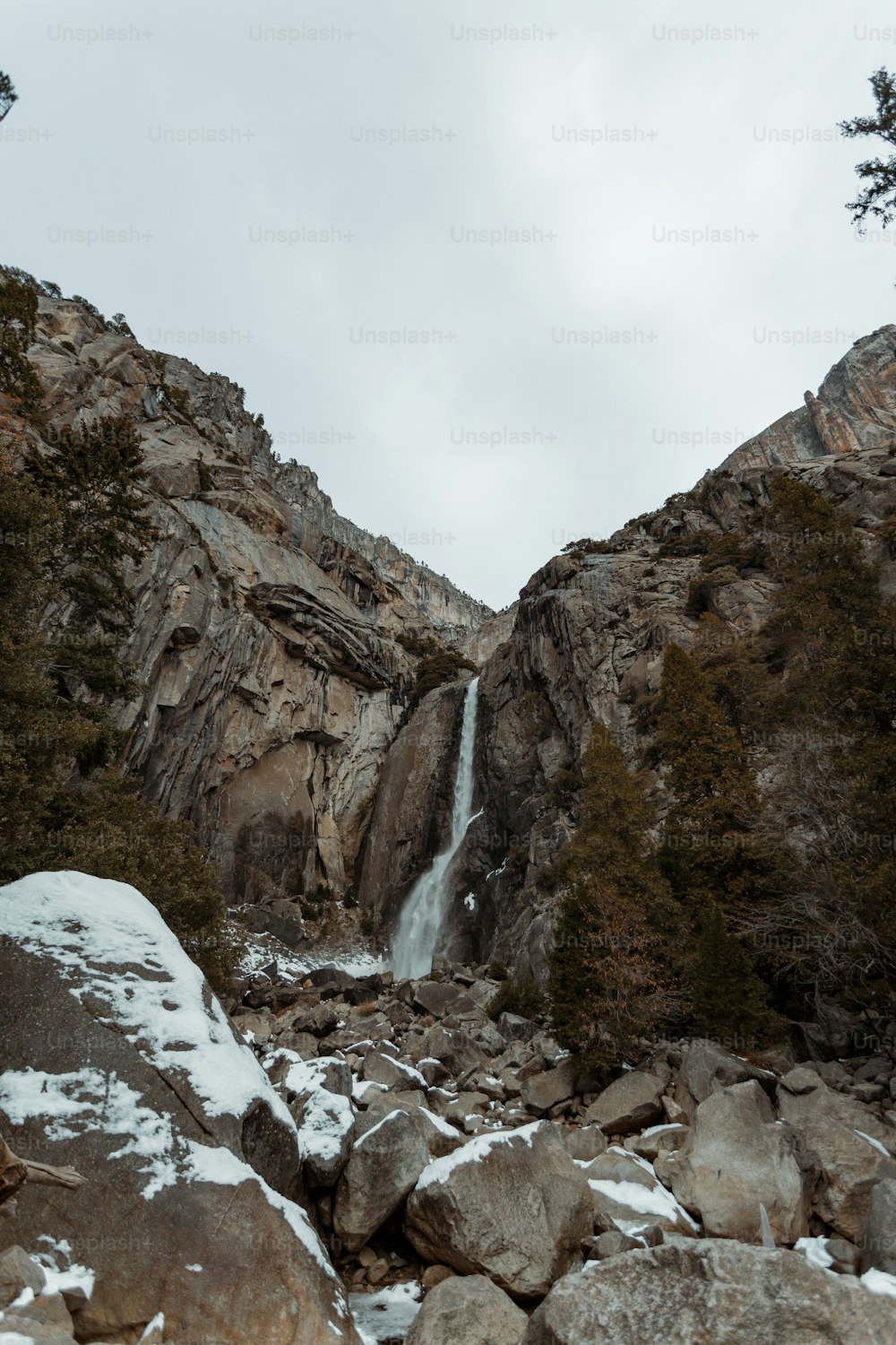 Ein Berg mit Wasserfall und Schnee auf dem Boden