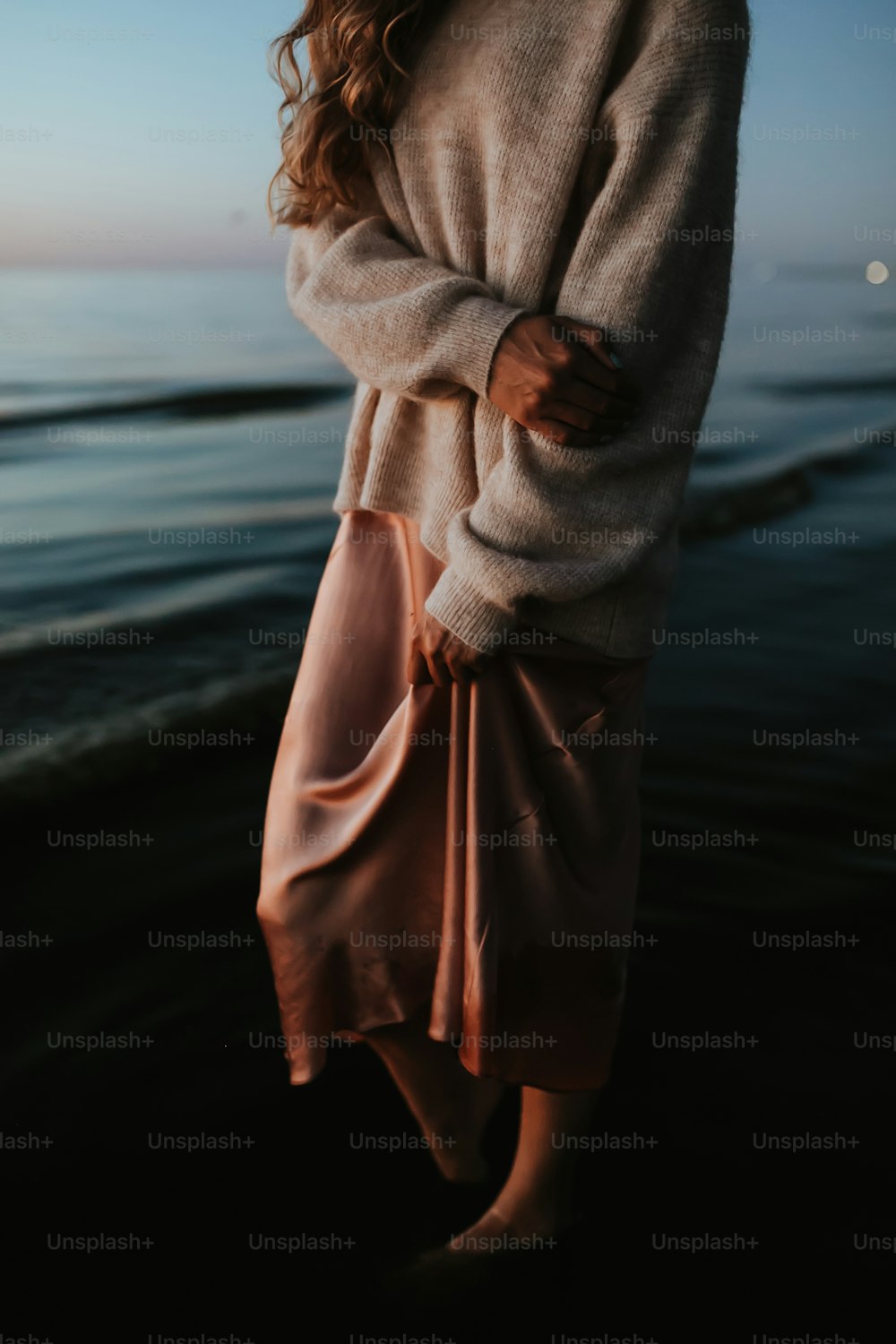 uma mulher em pé em uma praia ao lado do oceano