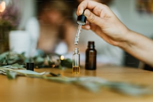 a person holding a dropper over a bottle of essential oils