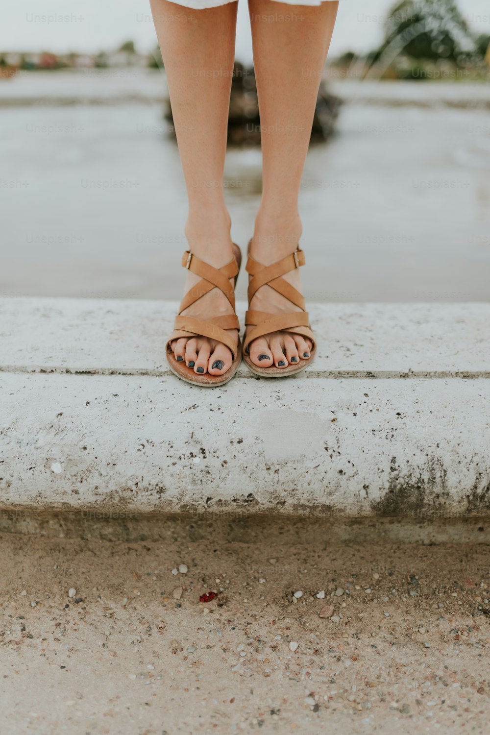 os pés de uma mulher em sandálias de pé em uma saliência