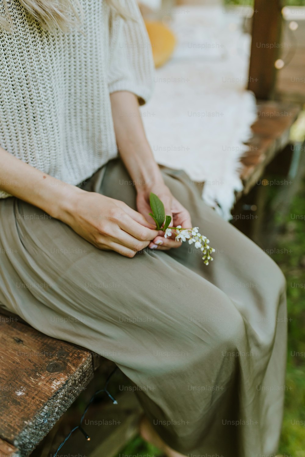 a woman sitting on a bench holding a flower