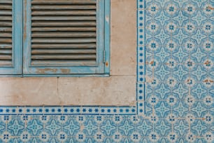 una parete piastrellata blu e bianca con una finestra