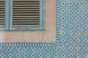 una pared de azulejos azules y blancos con una ventana