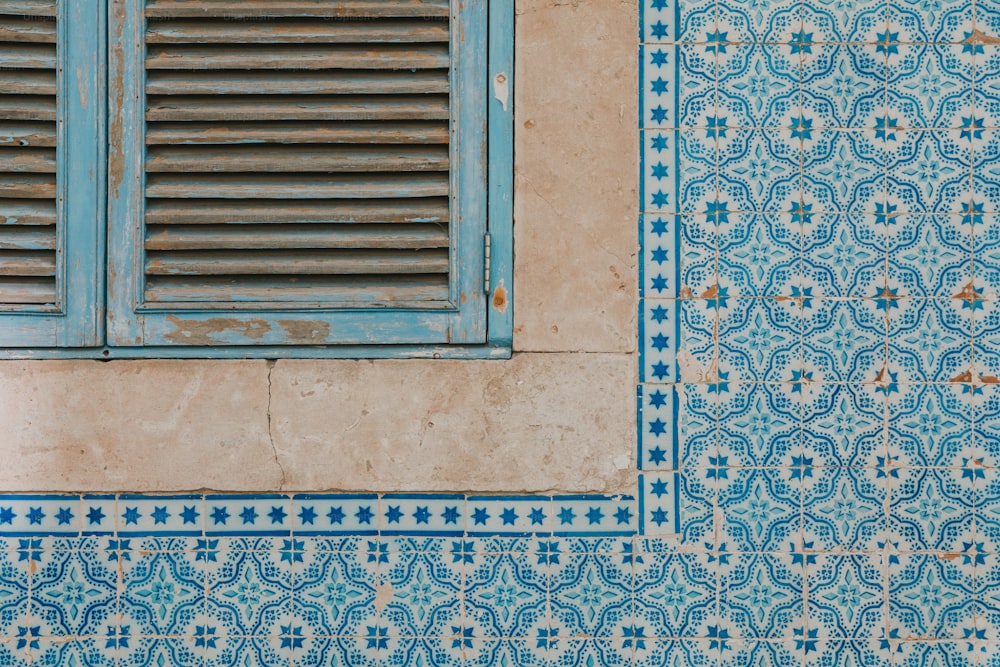 a blue and white tiled wall with a window