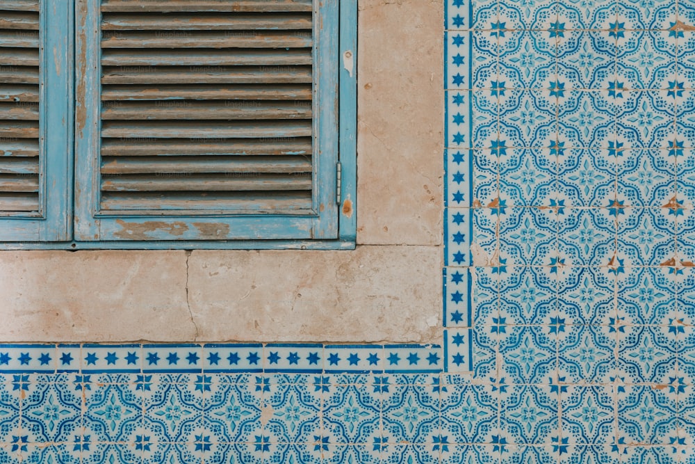uma parede de azulejos azuis e brancos com uma janela