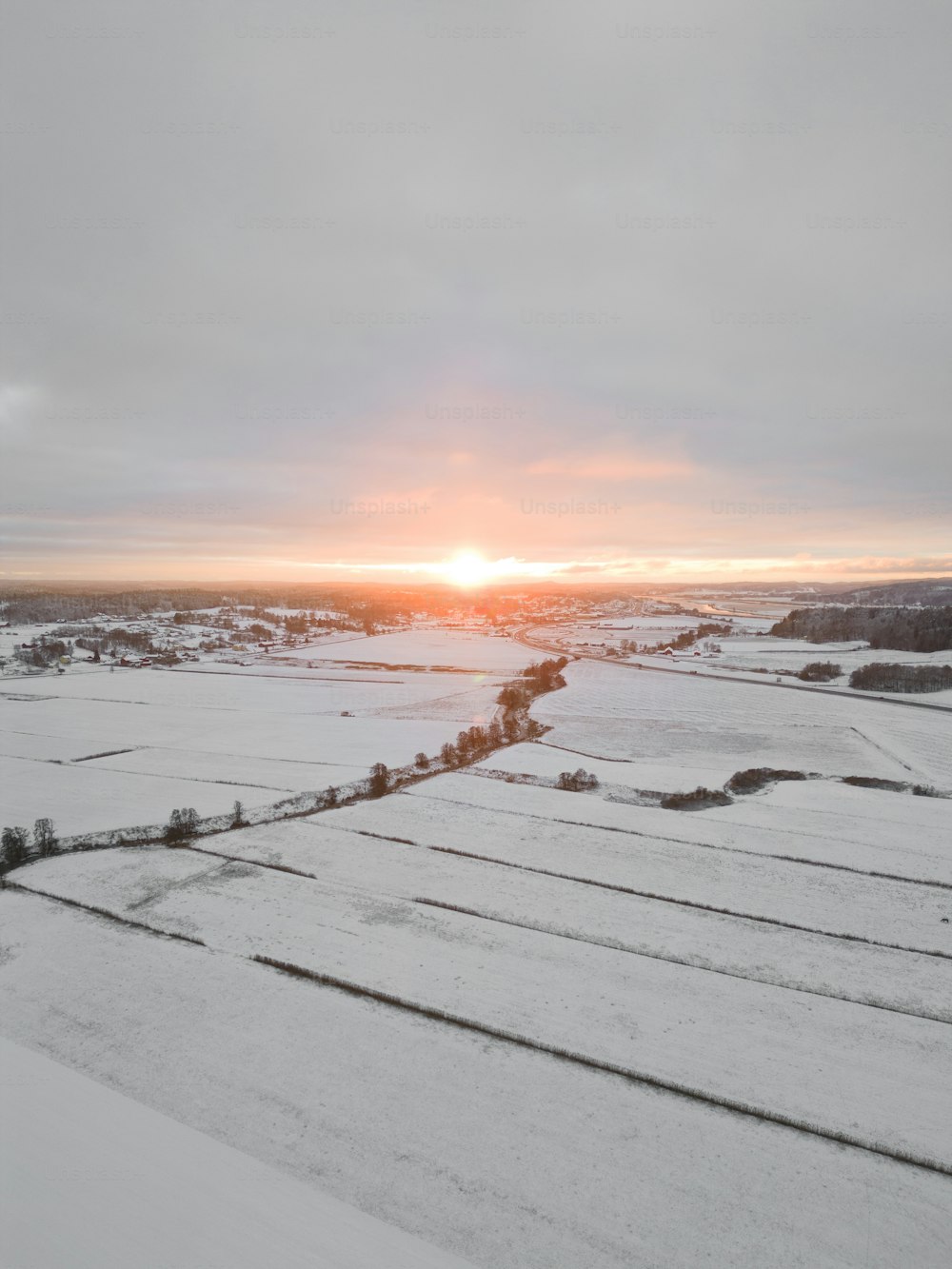 the sun is setting over a snowy field