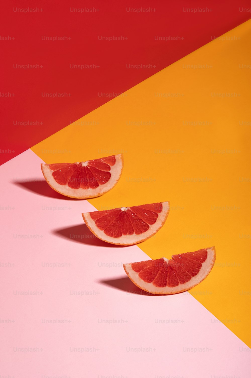 drei Scheiben Grapefruit auf mehrfarbigem Hintergrund
