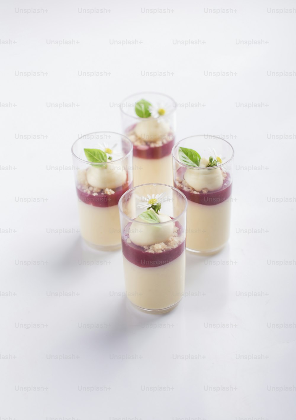 four glasses filled with dessert sitting on top of a table