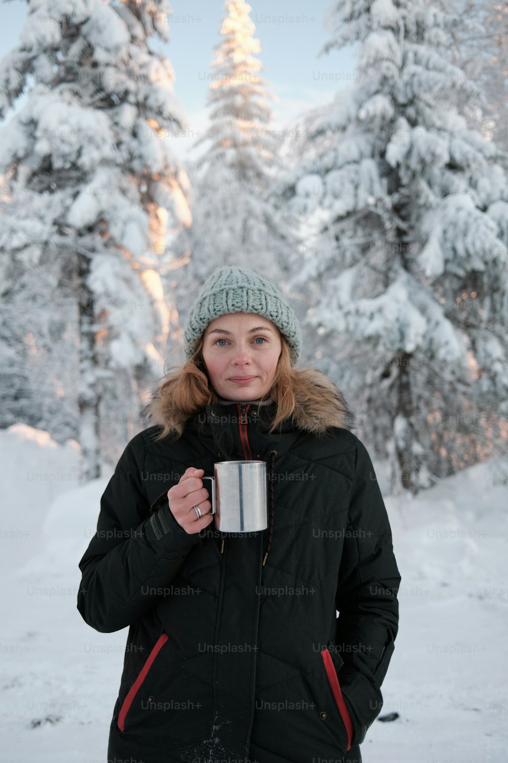 uma mulher de pé na neve segurando uma xícara de café