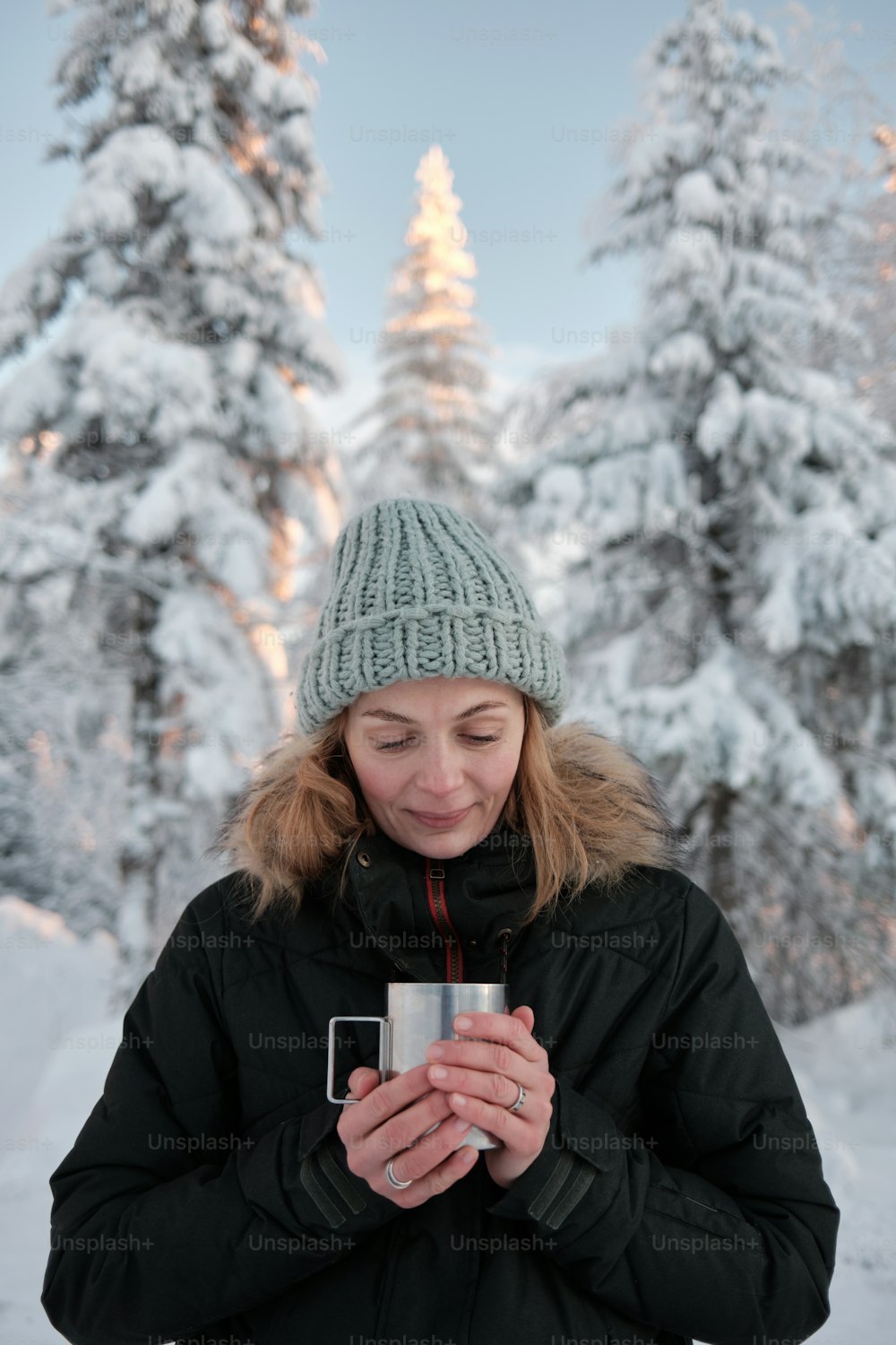 a woman standing in the snow holding a cup