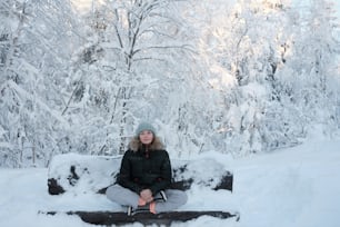 uma mulher sentada em um banco na neve