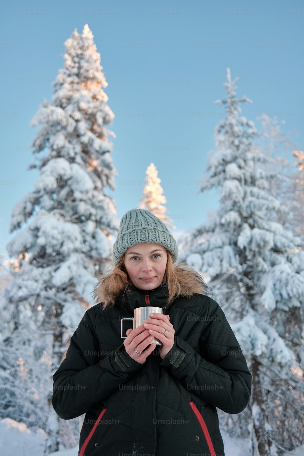 uma mulher em pé na neve segurando uma câmera