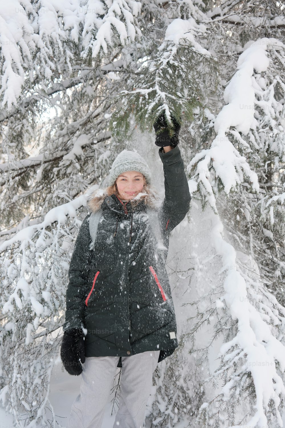uma mulher em pé na frente de uma árvore coberta de neve
