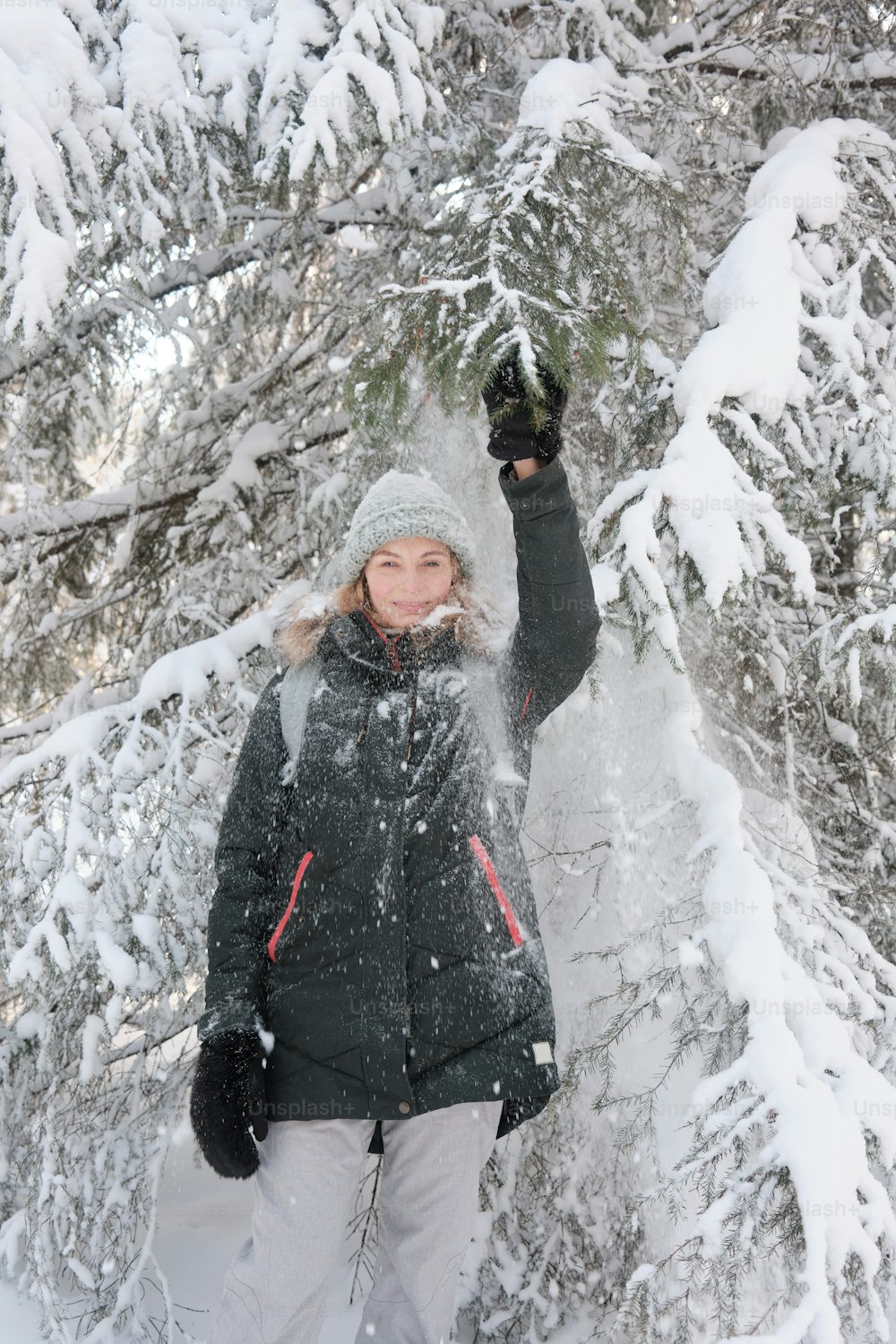 a woman standing in front of a snow covered tree