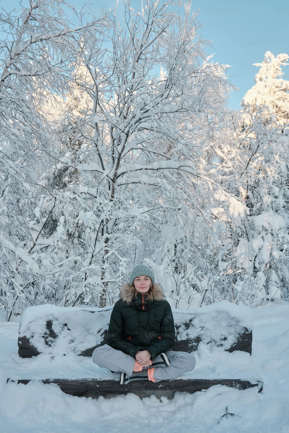 uma mulher sentada em um banco na neve